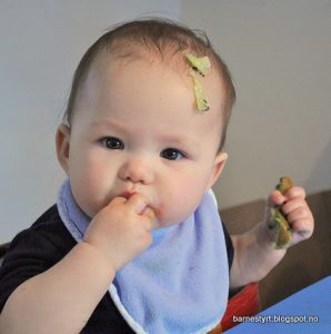 Barnestyrt mattilvenning -baby spiser med kiwi på hode.